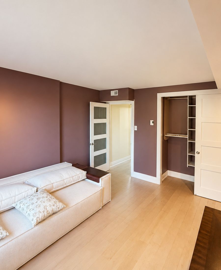 Bedroom with mauve plum walls, white ceiling, light bamboo hardwood floors, and a cream sofa in Manotick