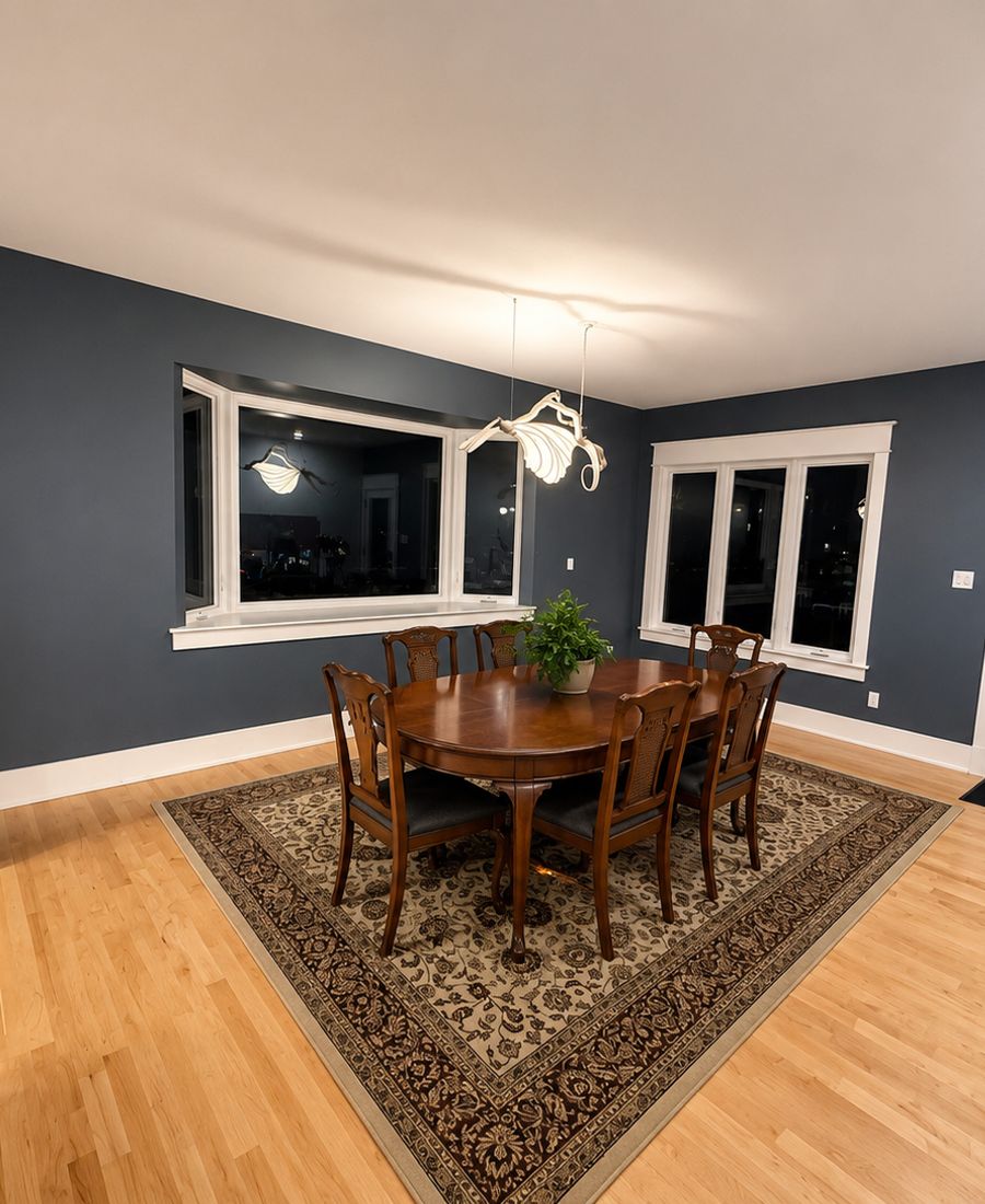 Freshly painted dining room with deep blue-grey walls, white trim, hardwood floors, and a dark wood dining set in Rockcliffe Park