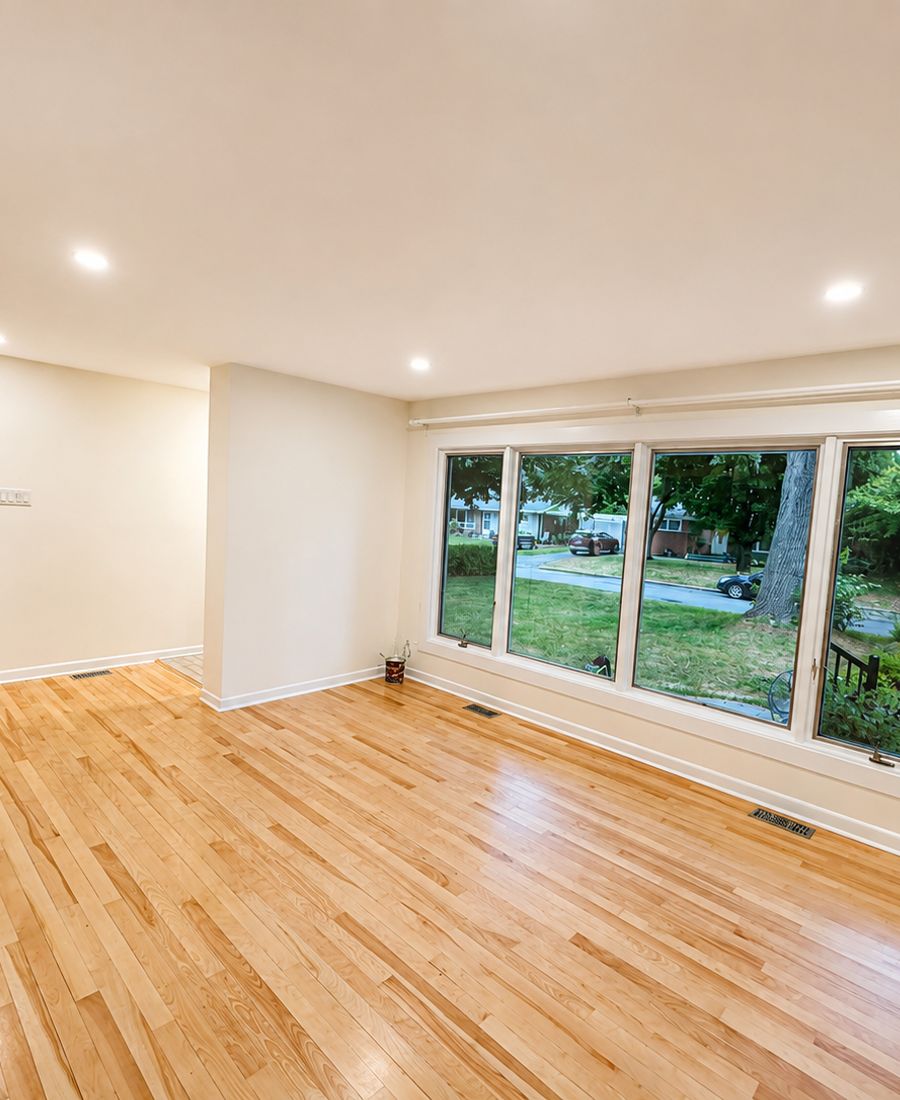 Bright living room with fresh white walls, refinished hardwood floors, and large picture windows in Kanata