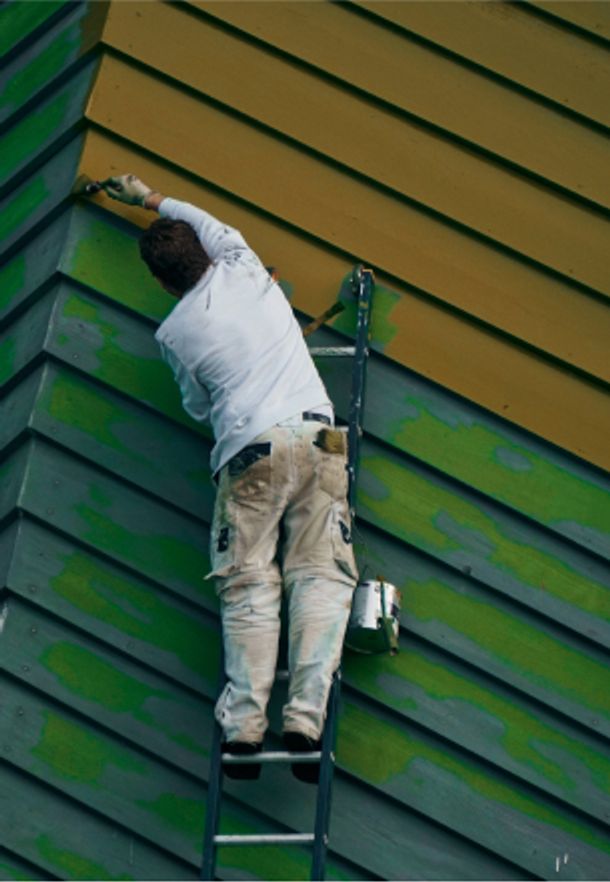 Man painting the outside of a house green
