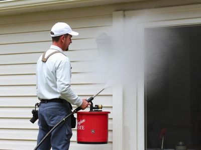 Painter pressure washing exterior siding before painting